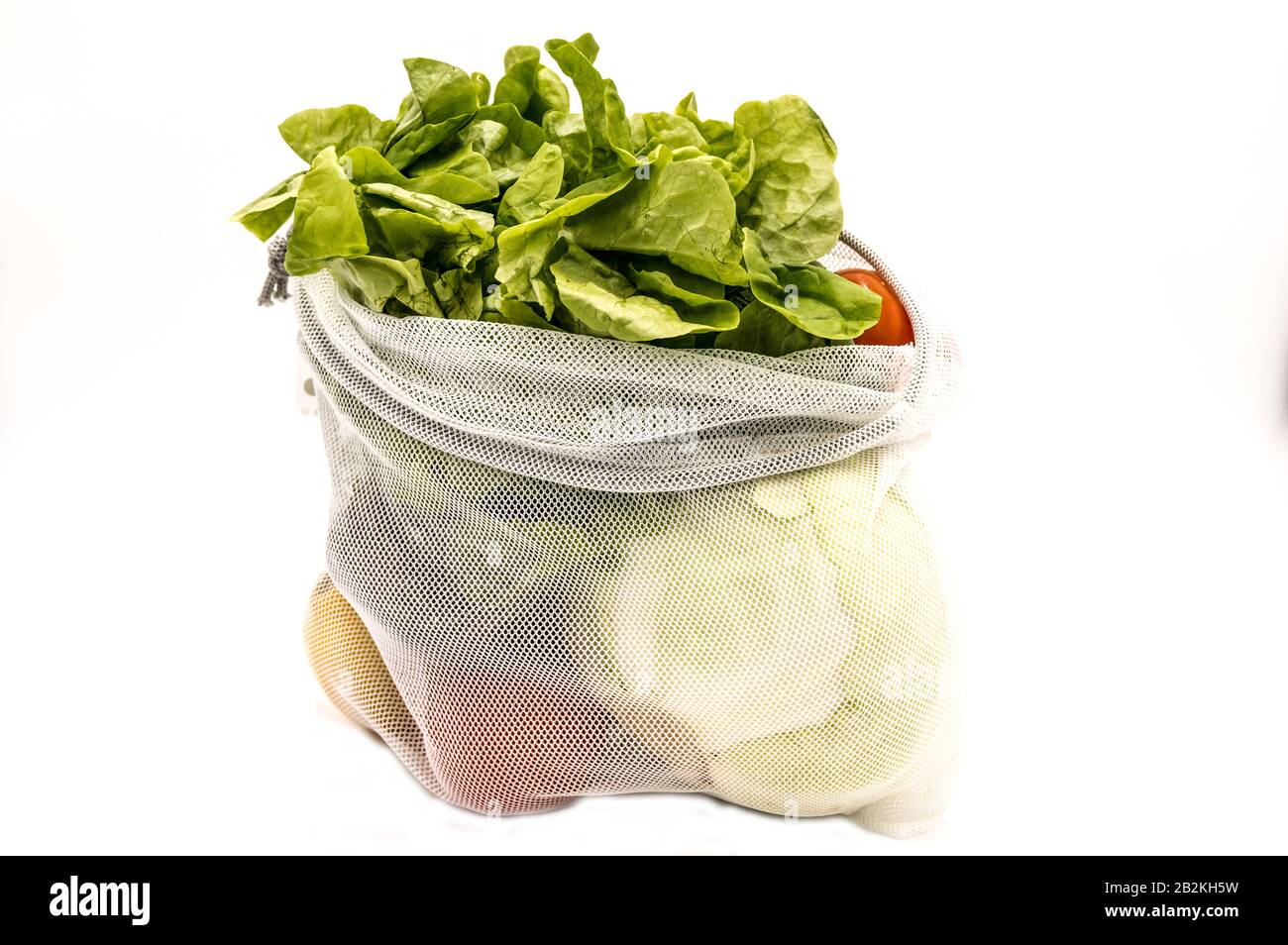 Vue en profil des légumes et des fruits dans un sac en mesh réutilisable sur fond blanc Banque D'Images Vue en profil des légumes et des fruits dans un sac en mesh réutilisable sur fond blanc Banque D'Images