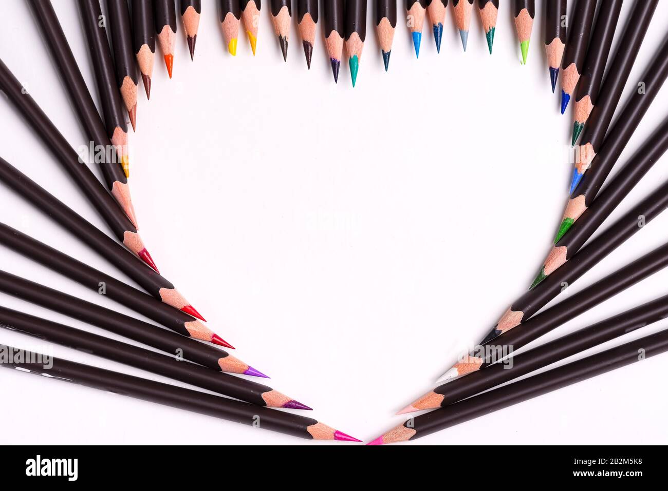 Motif de peinture à partir de crayons multicolores en forme de coeur sur un fond blanc avec espace de copie. Pose plate. Banque D'Images