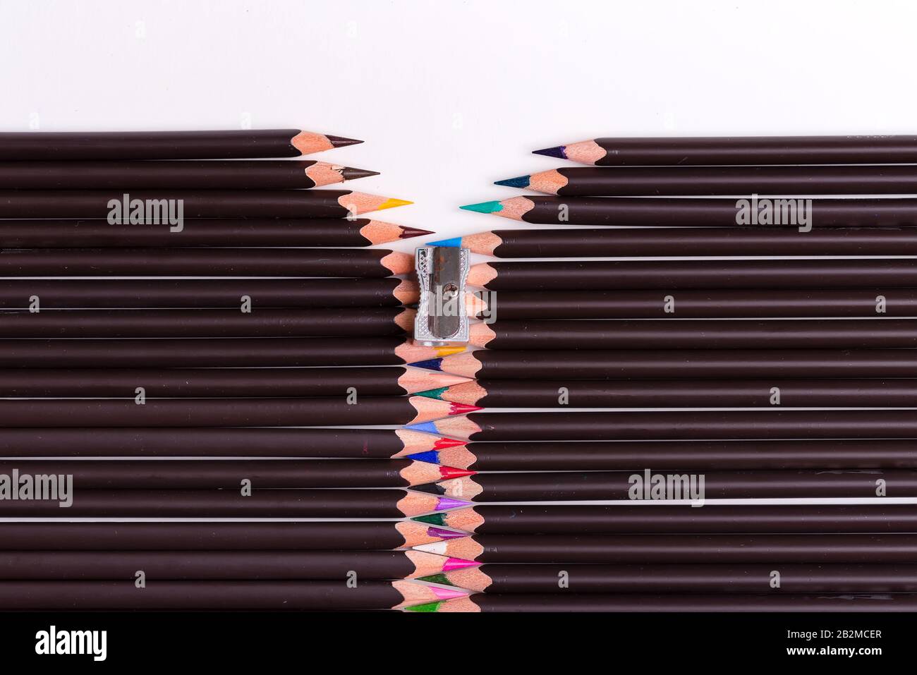 Motif créatif à partir de crayons multicolores et d'aiguiseur sous forme de fermeture éclair fixée sur un fond blanc avec espace de copie. Vue de dessus. Banque D'Images
