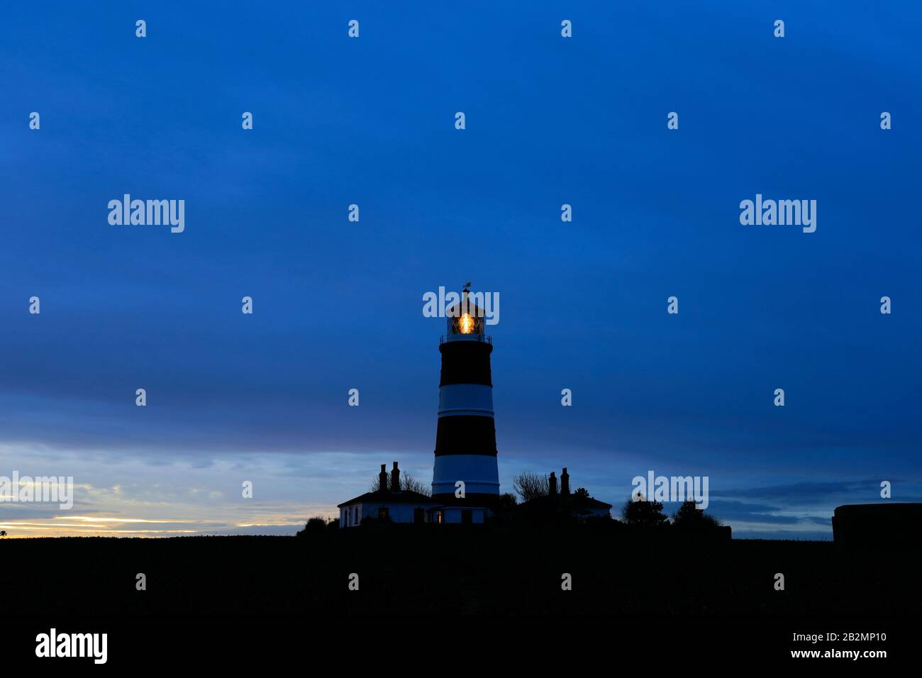 Coucher de soleil sur le phare de Happisburgh, village de Happisburgh, côte nord de Norfolk, Angleterre, Royaume-Uni son seul phare indépendant au Royaume-Uni. Banque D'Images
