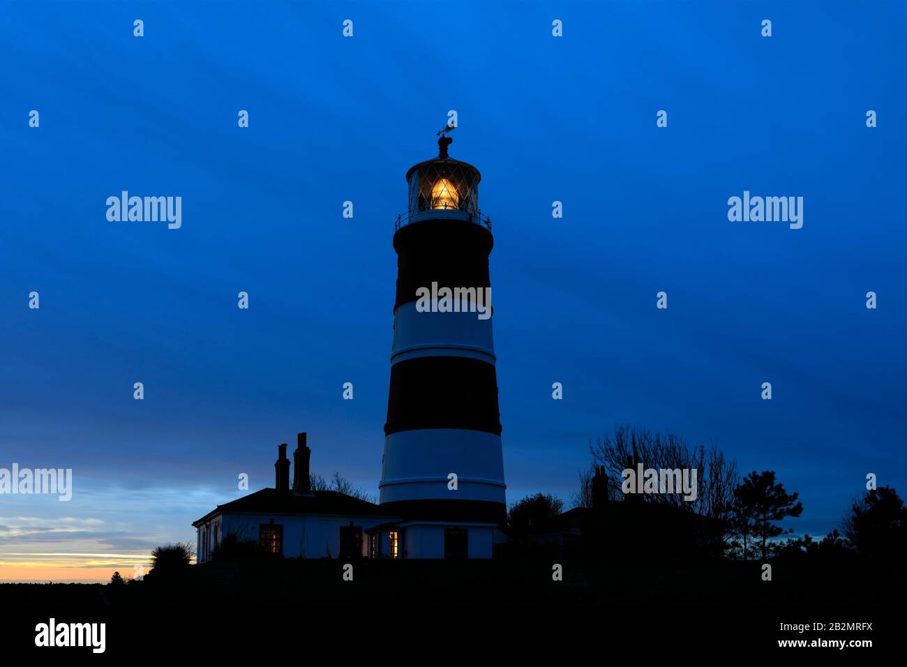 Coucher de soleil sur le phare de Happisburgh, village de Happisburgh, côte nord de Norfolk, Angleterre, Royaume-Uni son seul phare indépendant au Royaume-Uni. Banque D'Images