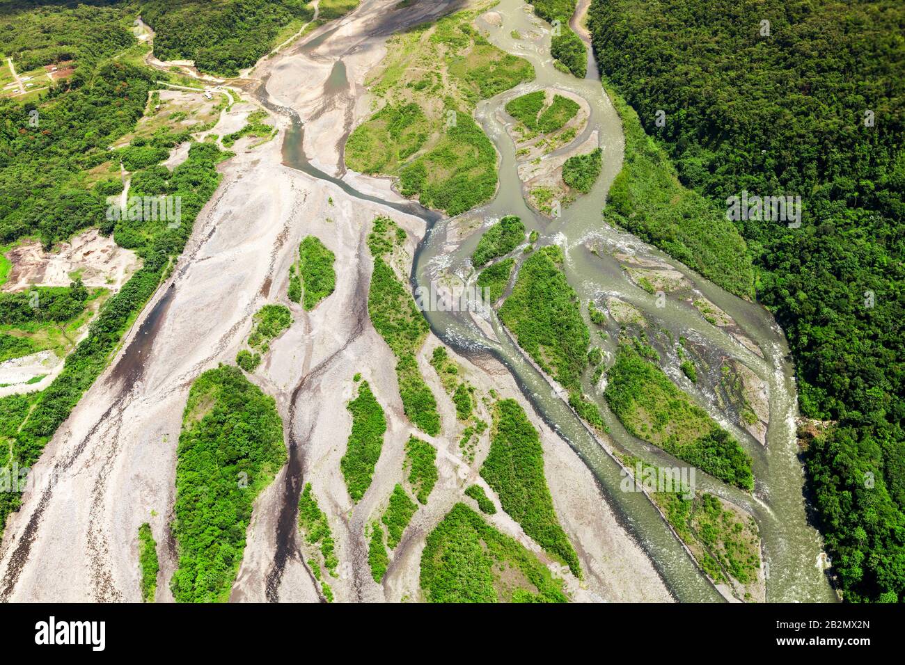 Une photographie aérienne montre une rivière sinueuse coupant à travers un paysage avec une déforestation importante. La rivière coule à travers un mélange de terre exposée, de couleur claire et de taches de vert dense Banque D'Images