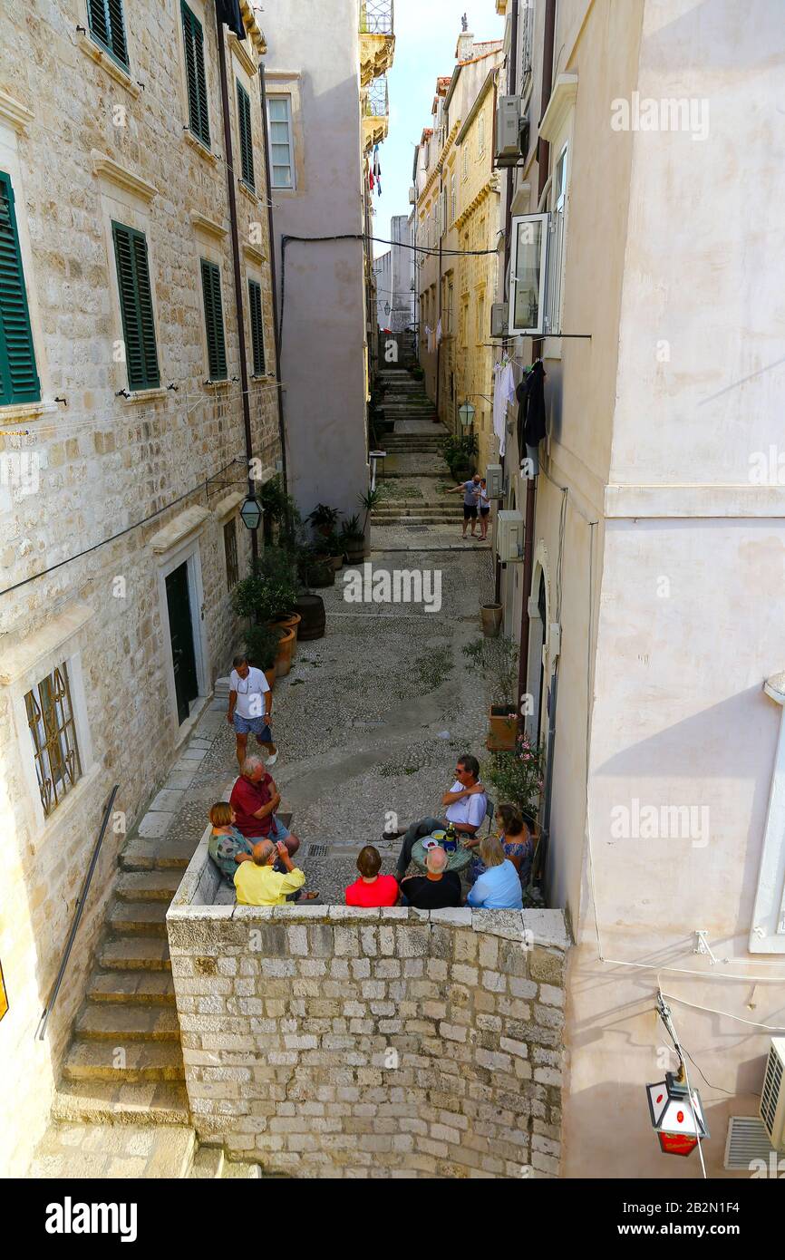 Personnes assises dans une rue étroite dans la vieille ville, Dubrovnik, Croatie Banque D'Images