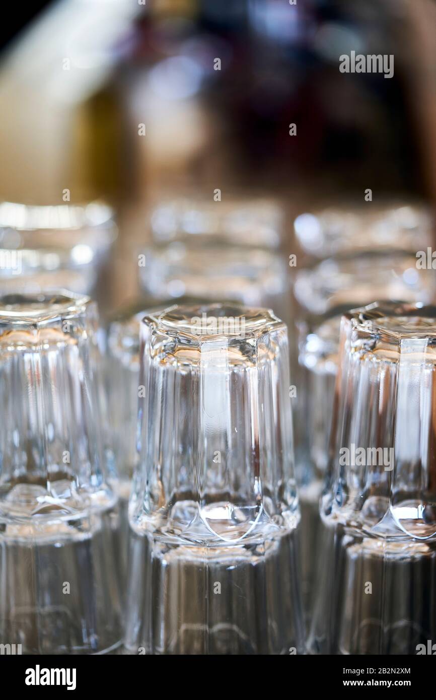 Rangées de verres dans un bar en attente d'utilisation. À l'arrière-plan, il y a des bouteilles de boissons alcoolisées. Banque D'Images