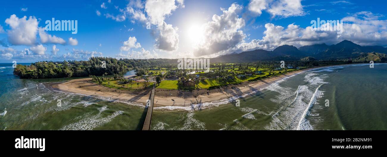Image panoramique aérienne au large de la côte au-dessus de la baie Hanalei et de la jetée sur l'île hawaïenne de Kauai alors que le soleil s'élève au-dessus du paysage dramatique Banque D'Images