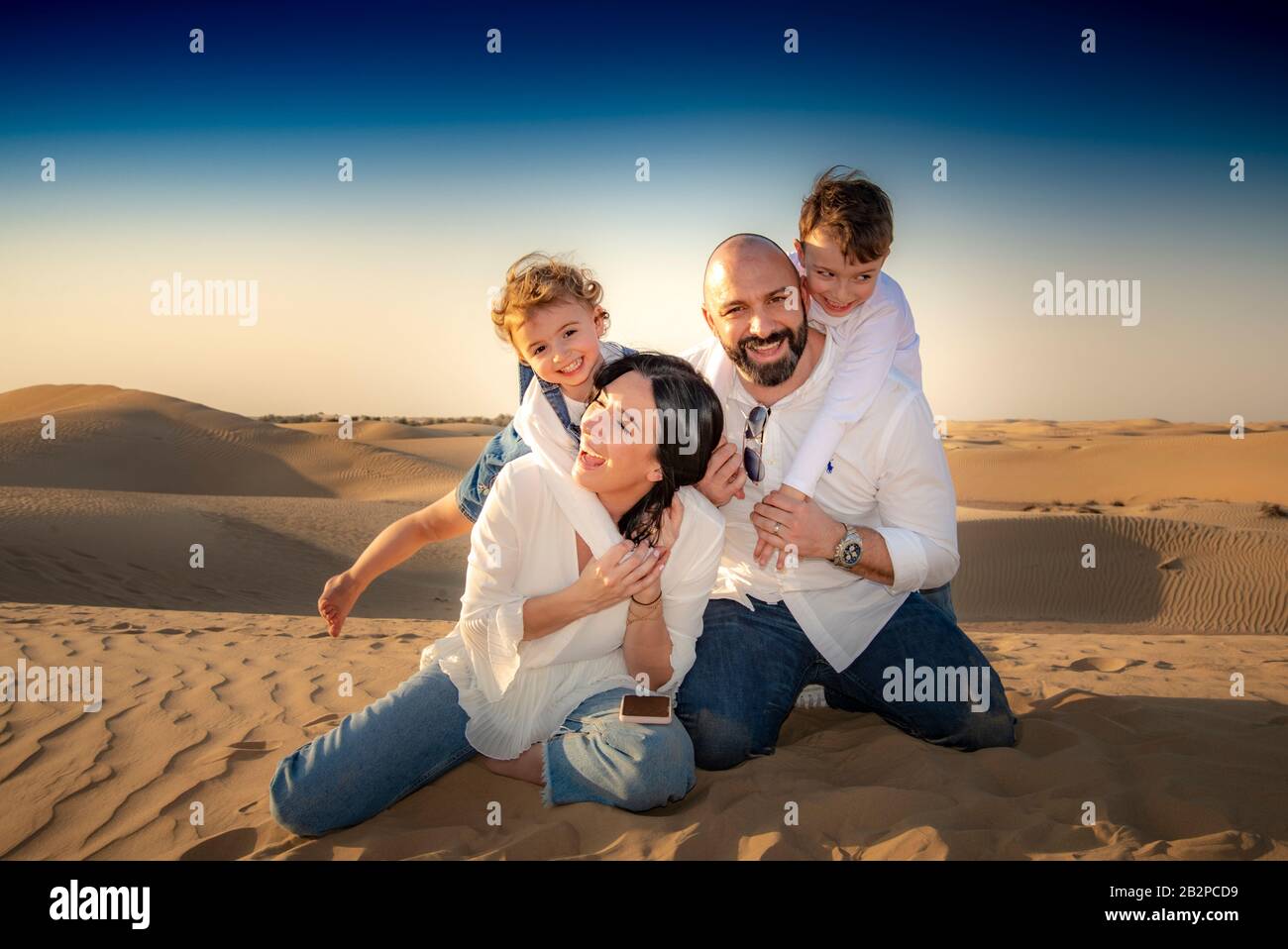 Portrait de groupe familial, se divertir ensemble, dans un désert avec des dunes de sable en arrière-plan, Dubaï, Banque D'Images