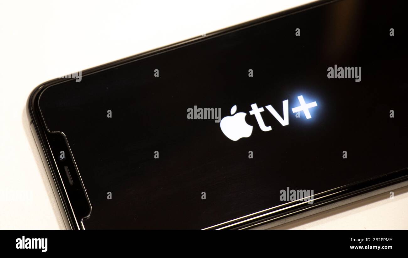 IPhone avec logo Apple TV + (plus) à l'écran lorsqu'il est placé sur une table blanche. Banque D'Images