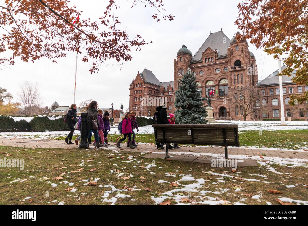 Un groupe de personnes se promenent sur un sentier devant l'Assemblée législative de l'Ontario, un après-midi enneigé. Banque D'Images