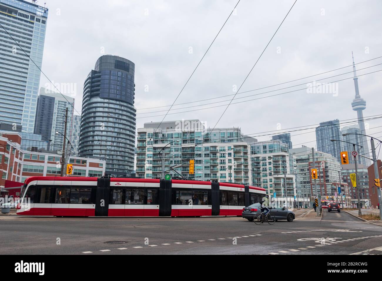 Un tramway Bombardier TTC est visible dans une rue animée de la ville avec les villes du centre-ville, la Tour CN en arrière-plan. Banque D'Images