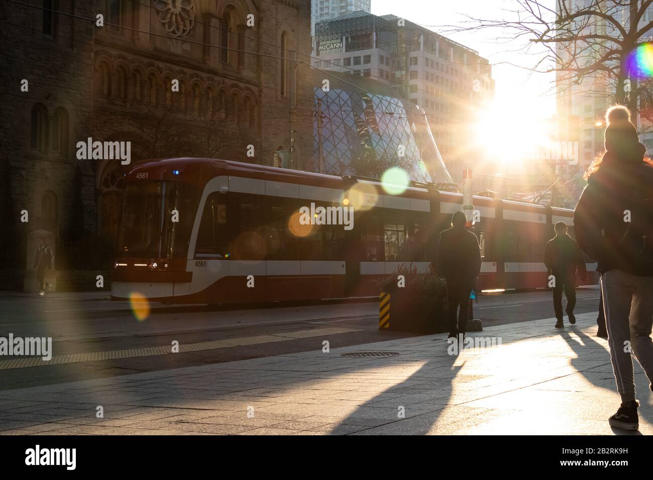 Le soleil se flait dans les édifices du centre-ville de Toronto sous forme de laissez-passer de tramway TTC par un trottoir animé. Banque D'Images