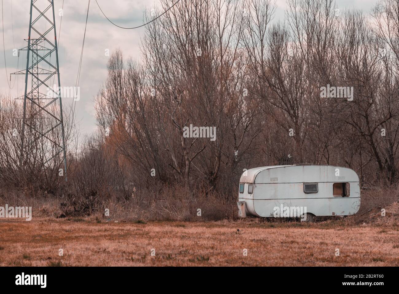 Remorque de voiture de camp abandonnée sur le terrain avec pylônes d'électricité Banque D'Images