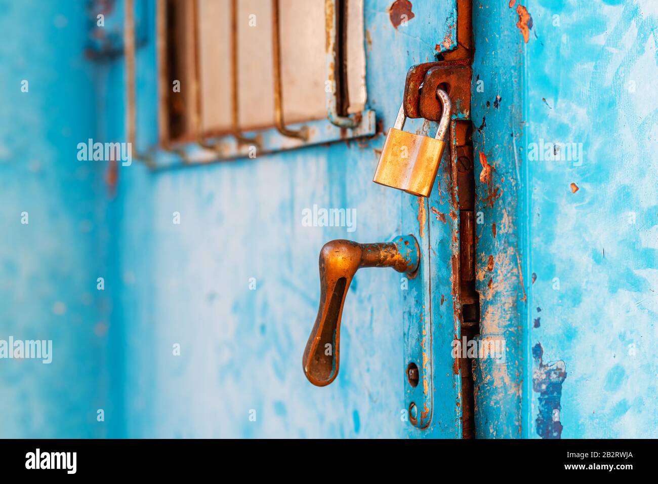Porte industrielle en métal ancien verrouillée avec cadenas en laiton, mise au point élective Banque D'Images