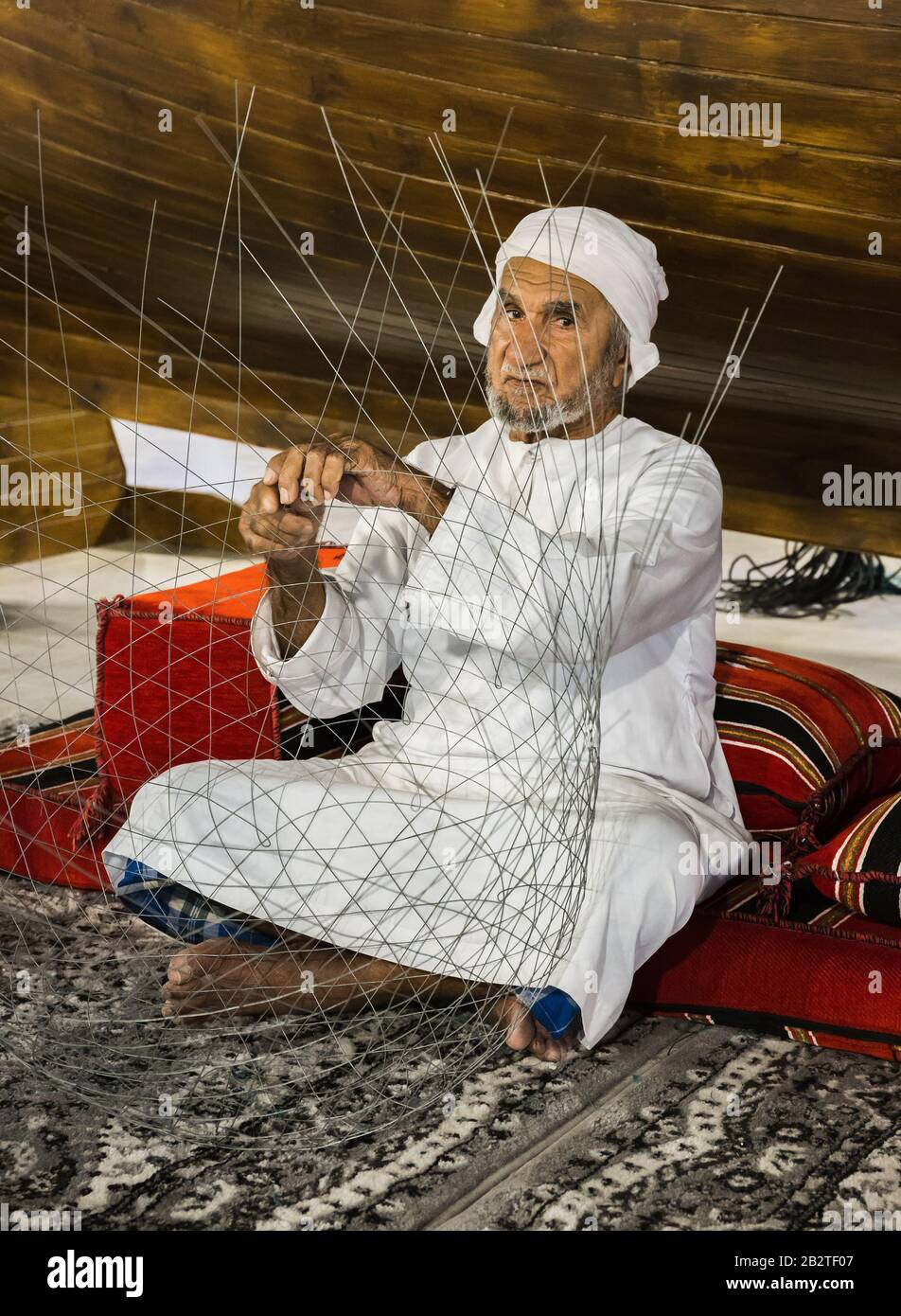 Dubaï, Émirats arabes Unis - 4 DÉCEMBRE 2017: Le vieil homme est en tissage un filet de pêche pour rencontrer des invités dans le pavillon des Émirats arabes Unis, Global Village Banque D'Images