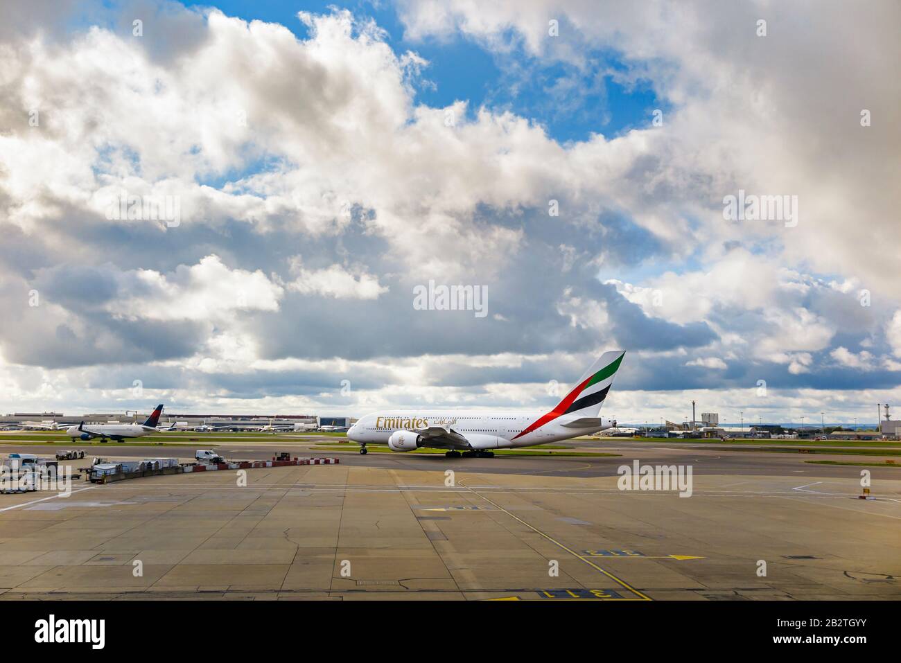 Emirates Airbus A 380-861 en privilège d'entreprise debout sur la piste de l'aéroport Heathrow de Londres sur la piste en attente de décollage sous de lourds nuages sombres Banque D'Images