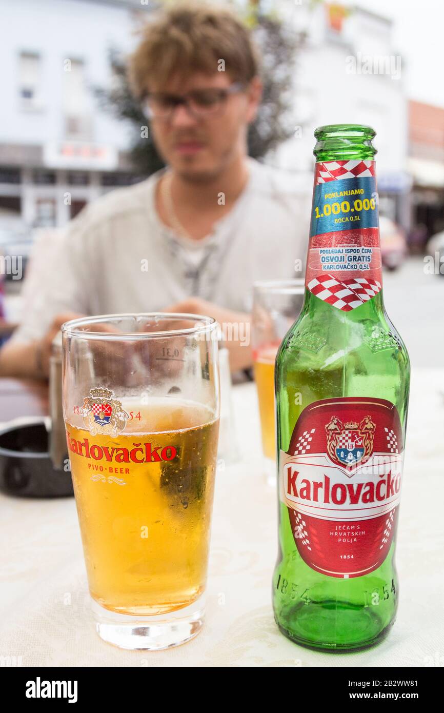 Osijek, CROATIE - 3 JUILLET 2016 : bouteille et verre de bière Karlovacko Pivo exposés sur la table du bar. Karlovacko est une bière légère, le mos Banque D'Images