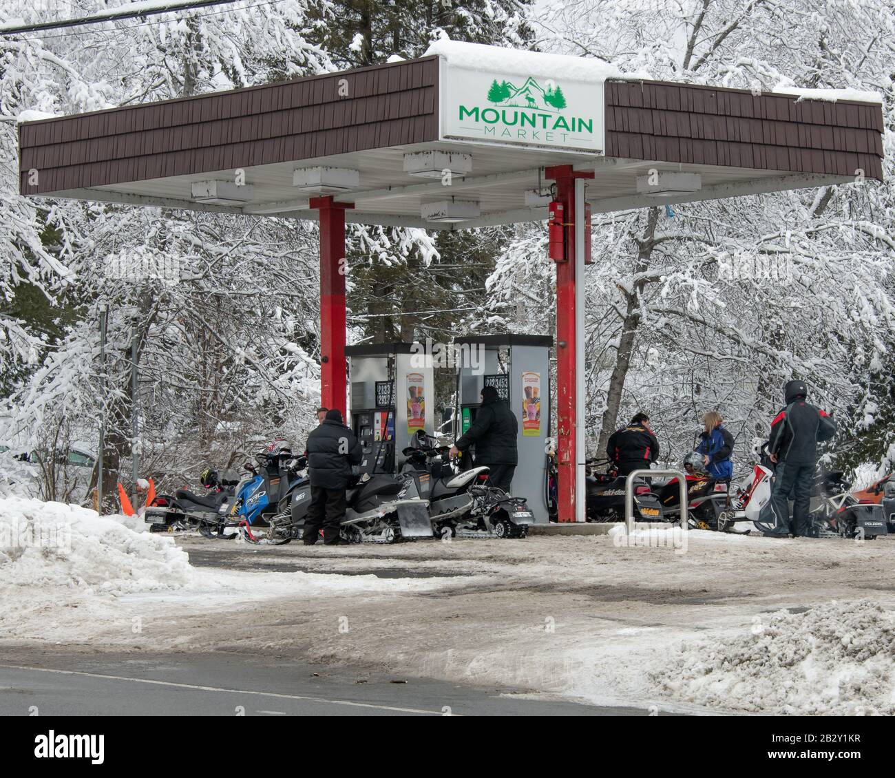 Un groupe de motoneigistes qui remplissent leurs motoneiges avec du carburant à la station-service Mountain Market de Speculator, NY USA Banque D'Images