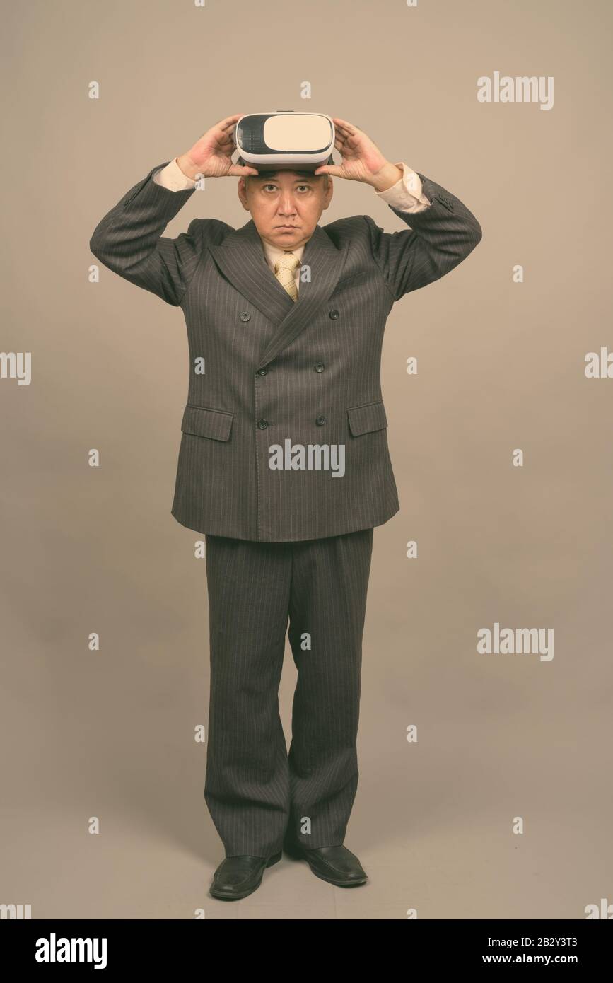 Portrait d'un homme d'affaires asiatique mûr à l'aide d'un casque de réalité virtuelle Banque D'Images