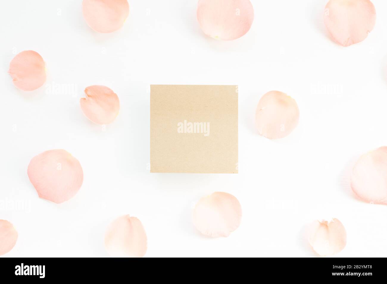 Papier mémo vide avec pétales de rose sur fond blanc. Composition florale, plat, vue de dessus, espace de copie Banque D'Images