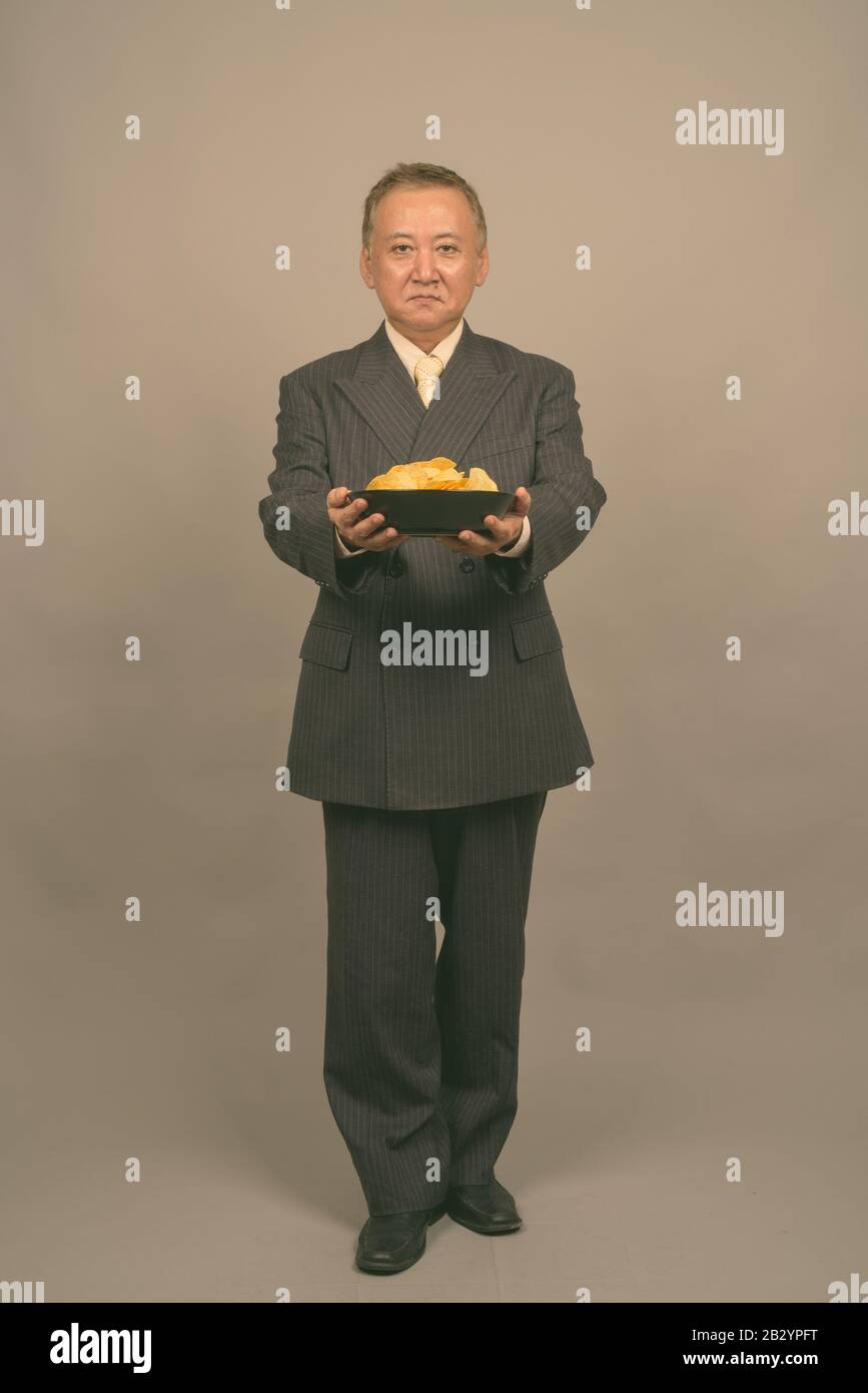 Portrait d'un homme d'affaires asiatique mûr avec un bol de chips de pommes de terre Banque D'Images