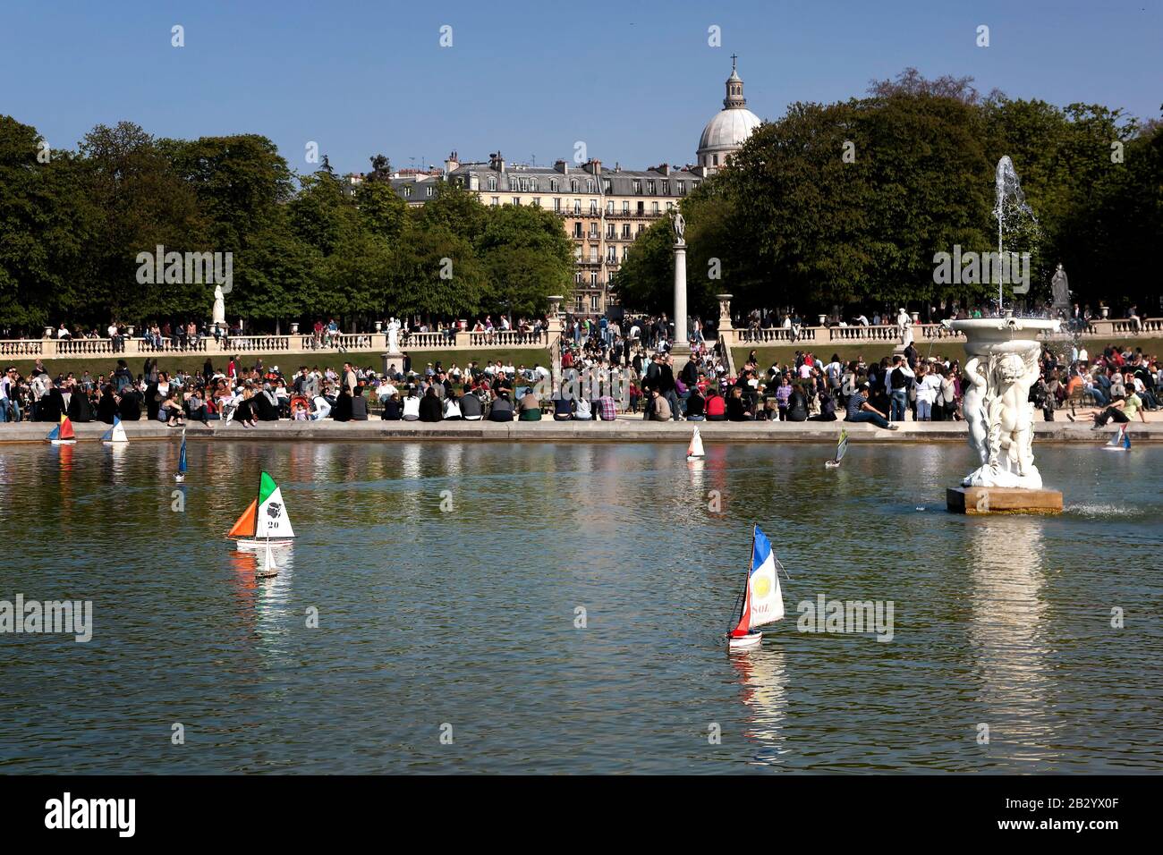 La vie quotidienne en France : les gens qui profitent d'un après-midi ensoleillé de printemps, les enfants poussent des voiliers en peluche sur l'étang de canard, le jardin du Luxembourg, Paris, France Banque D'Images