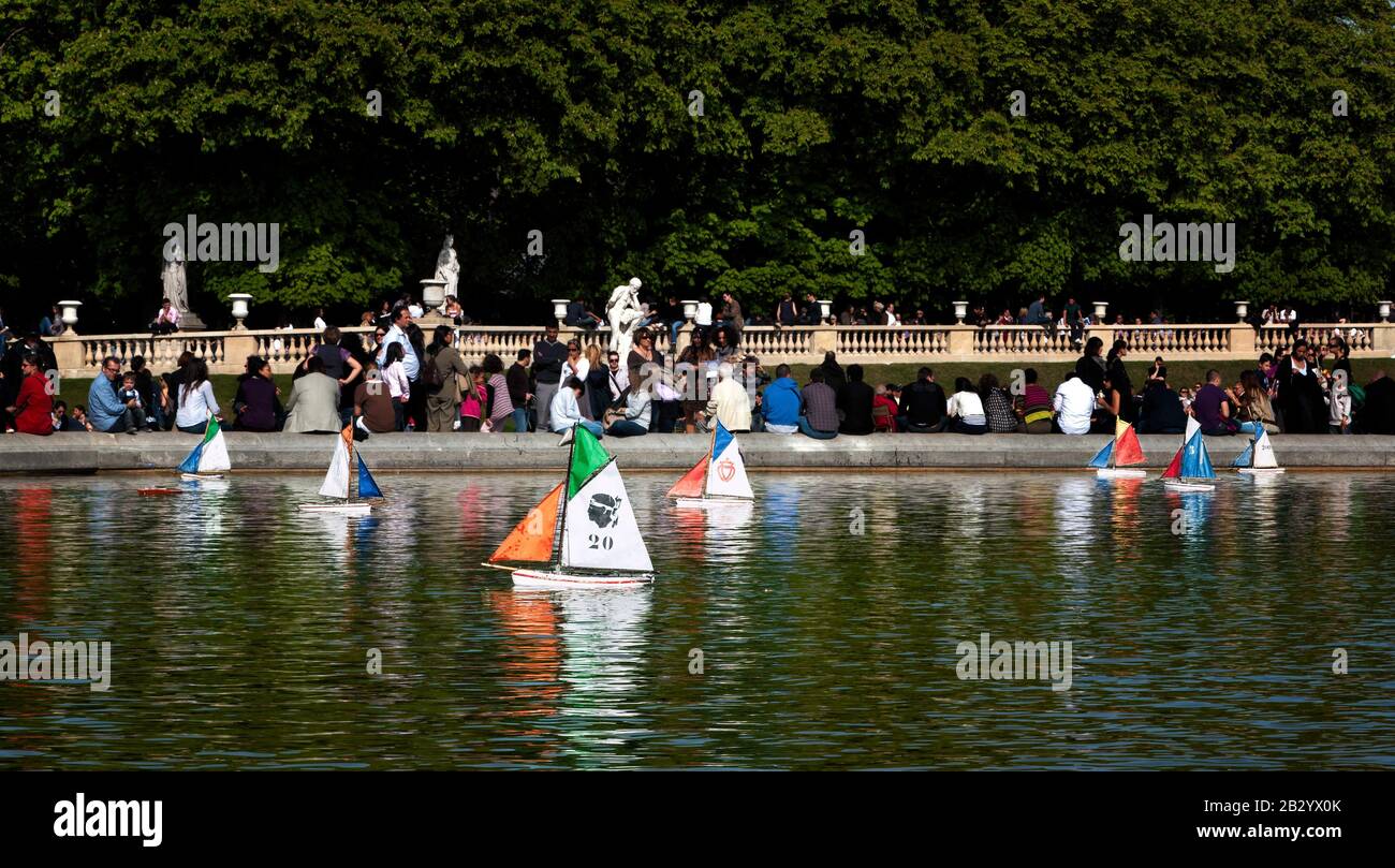 La vie quotidienne en France : les gens qui profitent d'un après-midi ensoleillé de printemps, les enfants poussent des voiliers en peluche sur l'étang de canard, le jardin du Luxembourg, Paris, France Banque D'Images