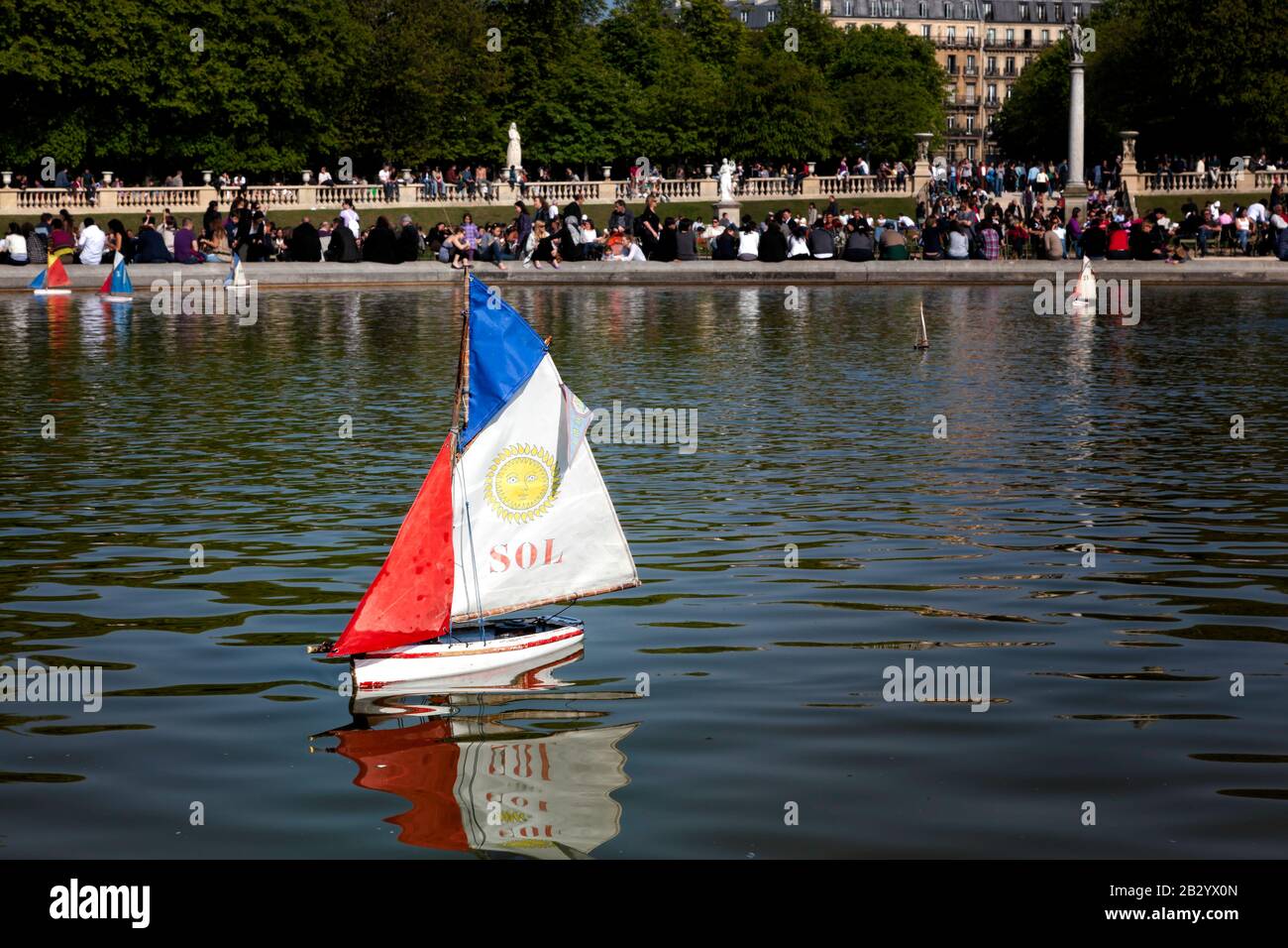 La vie quotidienne en France : les gens qui profitent d'un après-midi ensoleillé de printemps, les enfants poussent des voiliers en peluche sur l'étang de canard, le jardin du Luxembourg, Paris, France Banque D'Images