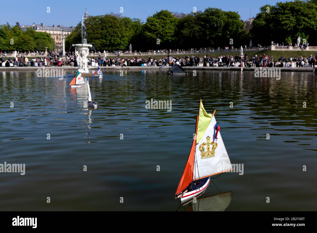 La vie quotidienne en France : les gens qui profitent d'un après-midi ensoleillé de printemps, les enfants poussent des voiliers en peluche sur l'étang de canard, le jardin du Luxembourg, Paris, France Banque D'Images