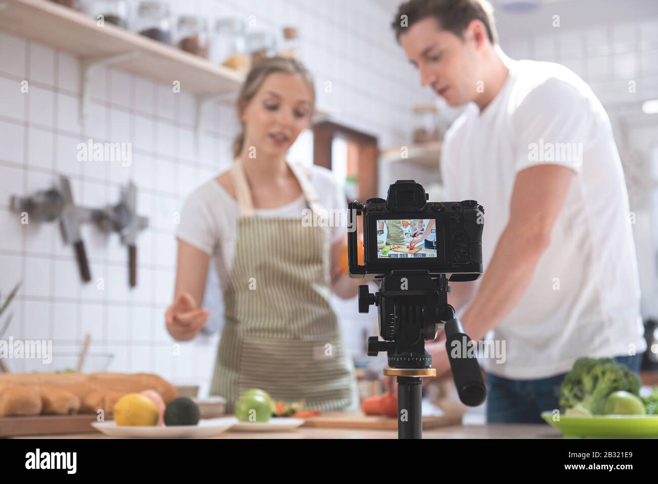 Photo numérique professionnel sans miroir enregistrement vidéo blog de heureux caucasien couple cuisiner dans la salle de cuisine, appareil photo pour photographe ou vidéo Banque D'Images