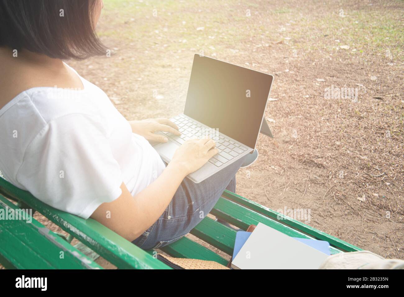 Vue arrière de l'entrepreneur asiatique moyen adulte femme d'affaires s'asseoir dans le parc en utilisant un ordinateur portable pour travailler à l'extérieur de bureau dans une robe décontractée look ordinateur portable avec thinkin Banque D'Images