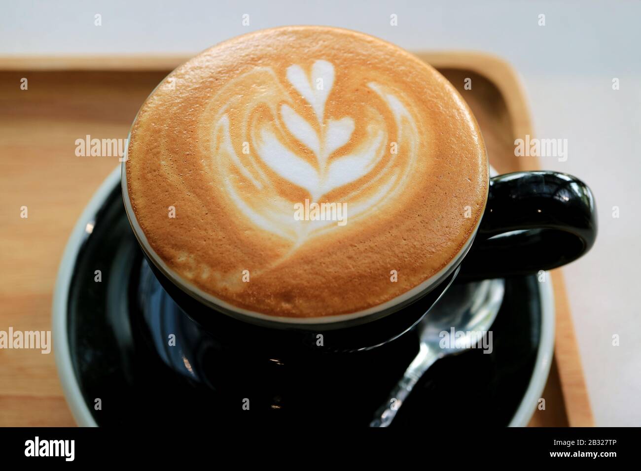 Tasse de café cappuccino avec de l'art latte sur un plateau en bois Banque D'Images