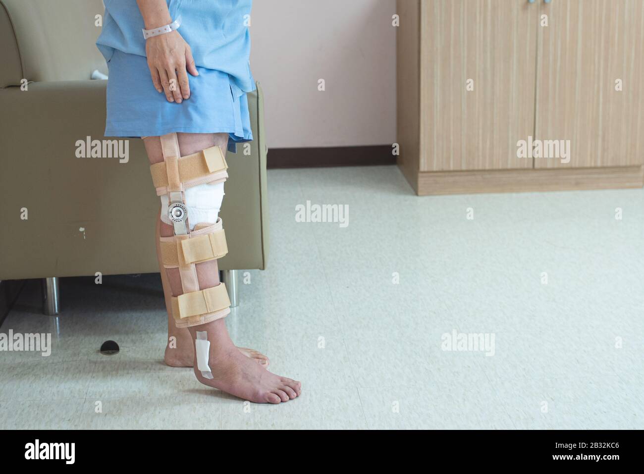 Patient debout avec le soutien de l'étrésillon de genou et du plâtre après la chirurgie du genou du ligament pcl dans l'hôpital orthopédique, le rétablissement et le concept de soins de santé. Banque D'Images