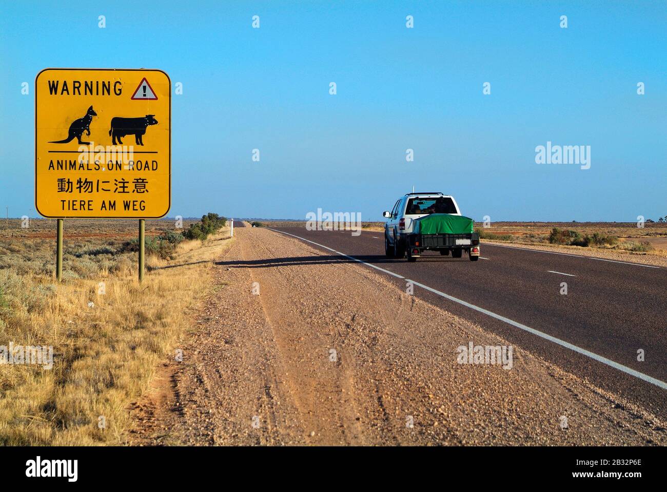 Australie, voiture sur l'autoroute Stuart de 3300 km de long d'Adélaïde à Darwin avec panneau d'avertissement dans différentes langues Banque D'Images