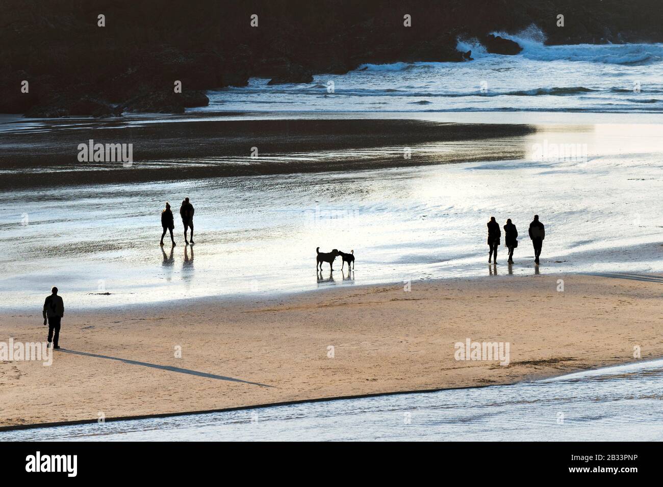 Les gens se sont enorgés par la lumière du soir lorsqu'ils marchent sur la plage de Porth à Newquay, dans les Cornouailles. Banque D'Images