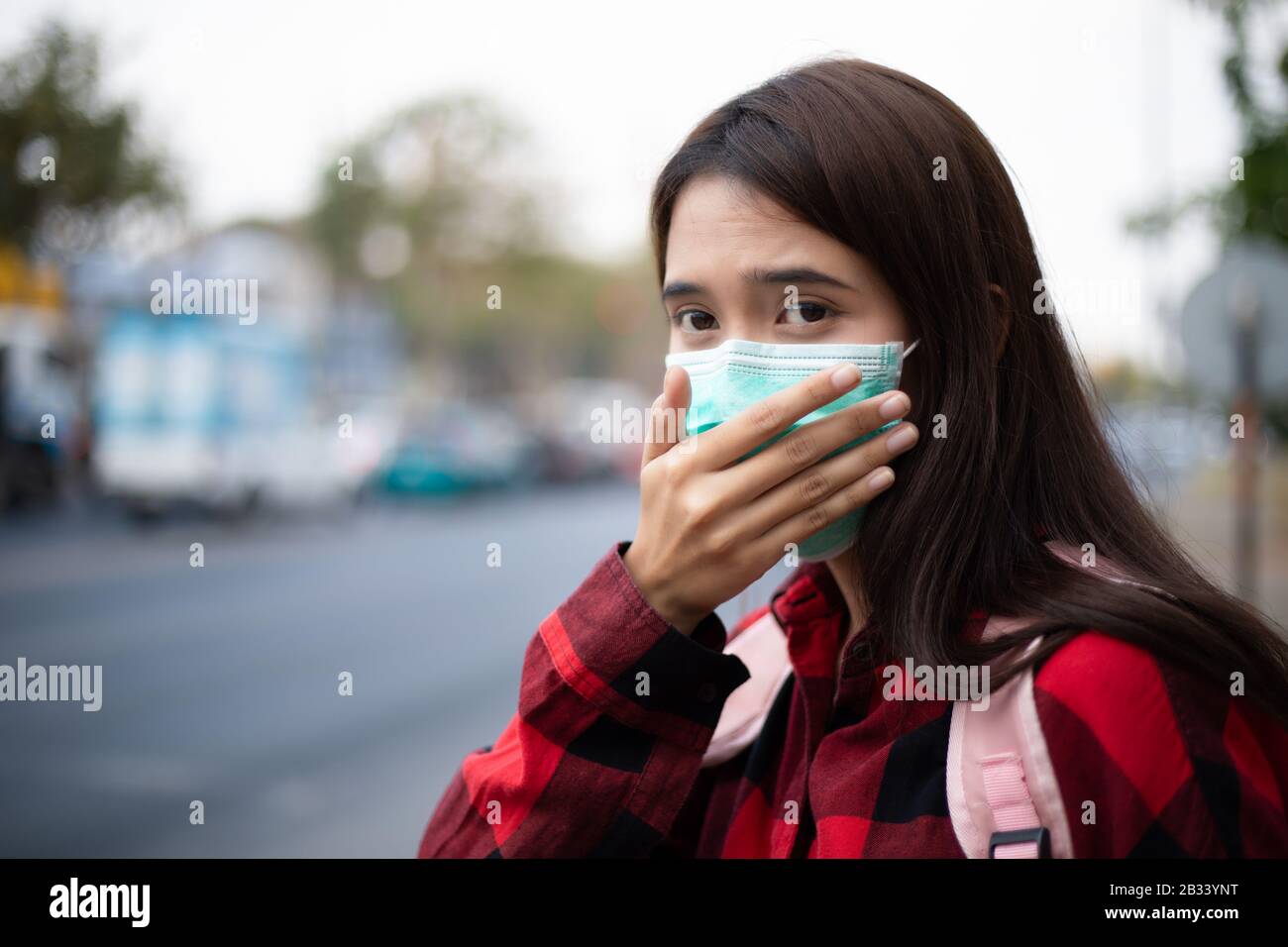 Jeune femme asiatique marchant dans la ville portant un masque facial en raison de la pollution de l'air, des particules et pour la protection du virus de la grippe, de la grippe, du coronavirus Banque D'Images