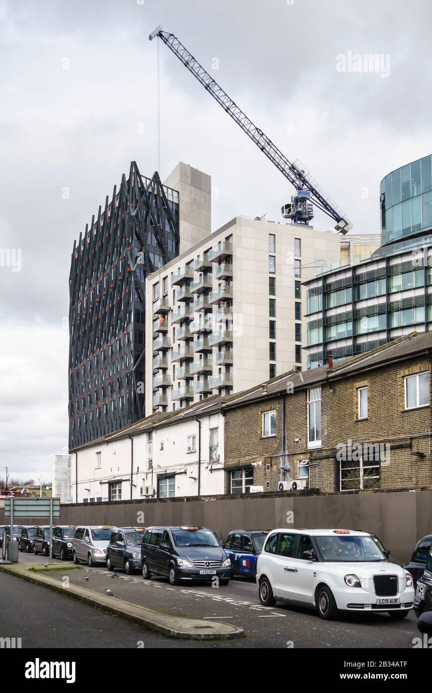 Des taxis sont alignés devant la gare de Paddington, Londres, Royaume-Uni, avec le nouveau bâtiment Brunel sur le bassin de Paddington en construction en arrière-plan Banque D'Images
