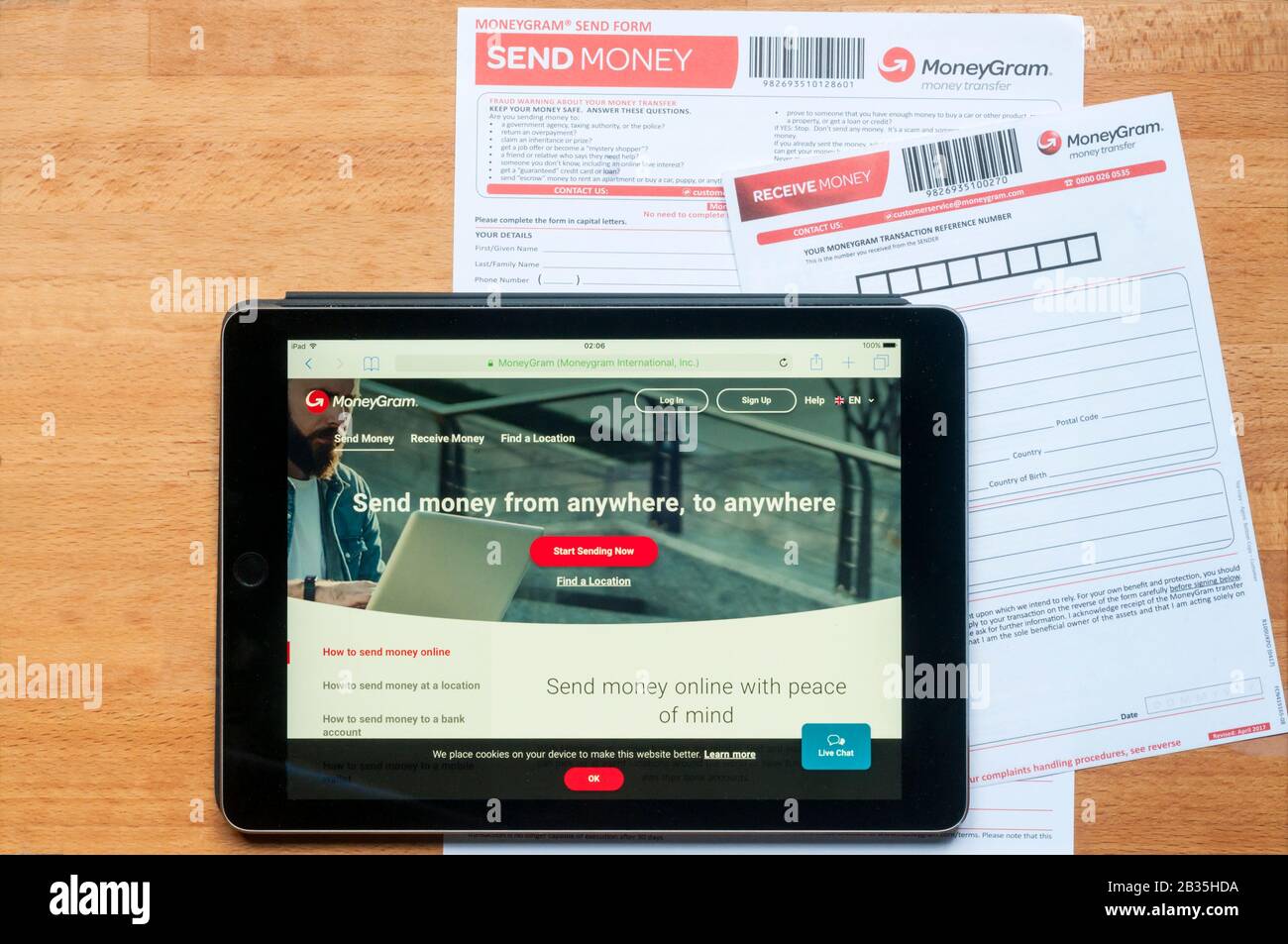 Le site de transfert d'argent moneygram affiché sur une tablette ipad ainsi que des formulaires imprimés pour l'envoi et la réception d'argent. Banque D'Images
