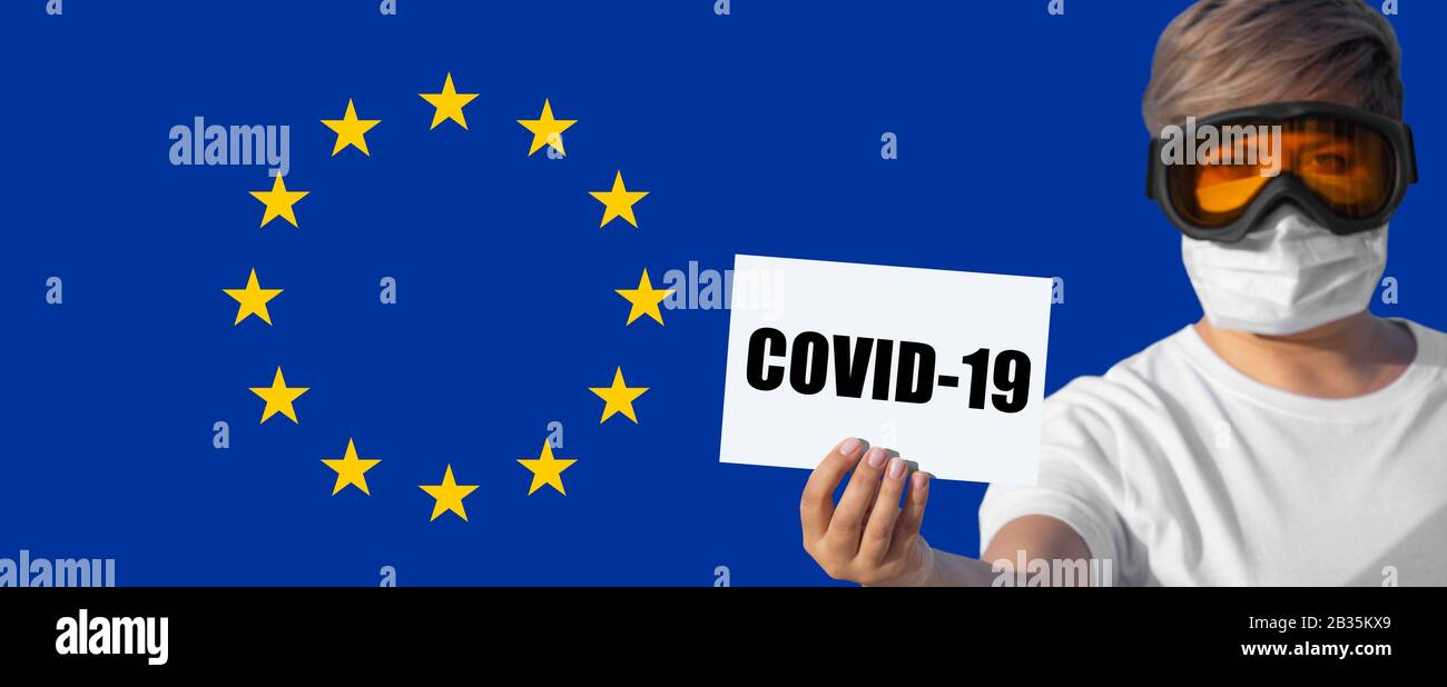 Femme en masque et lunettes de protection pour les yeux avec inscription COVID-19 contre le drapeau de l'Union européenne. Concept d'attention sur la propagation du virus chinois De La Pneumonie à Coronavirus COVID-19 dans le monde entier Banque D'Images