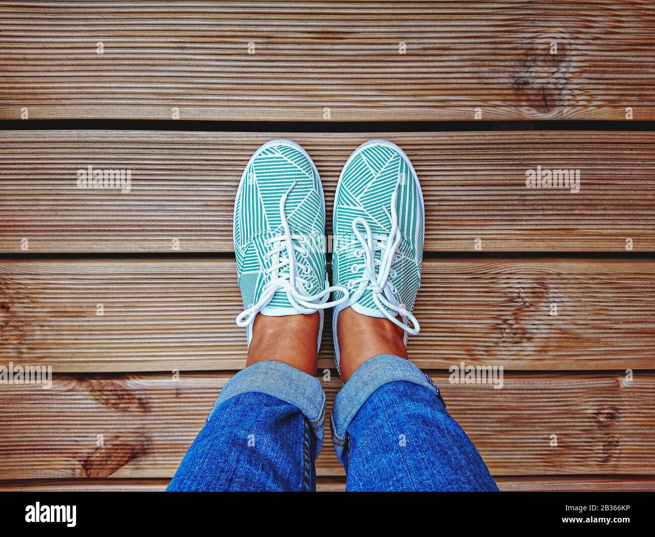 Jambes pour Femme en Sneakers vertes menthe sur la terrasse avec espace de copie. Vue de dessus et point de vue personnel Banque D'Images