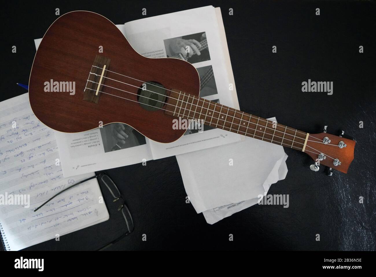 Note musicale, lunettes et ukulele sur fond noir Banque D'Images