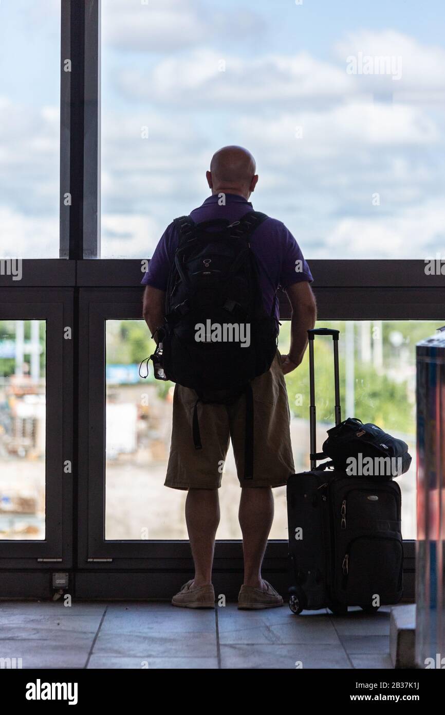 Homme regardant par une fenêtre avec des bagages à un terminal de train à Bâle, Suisse. Banque D'Images