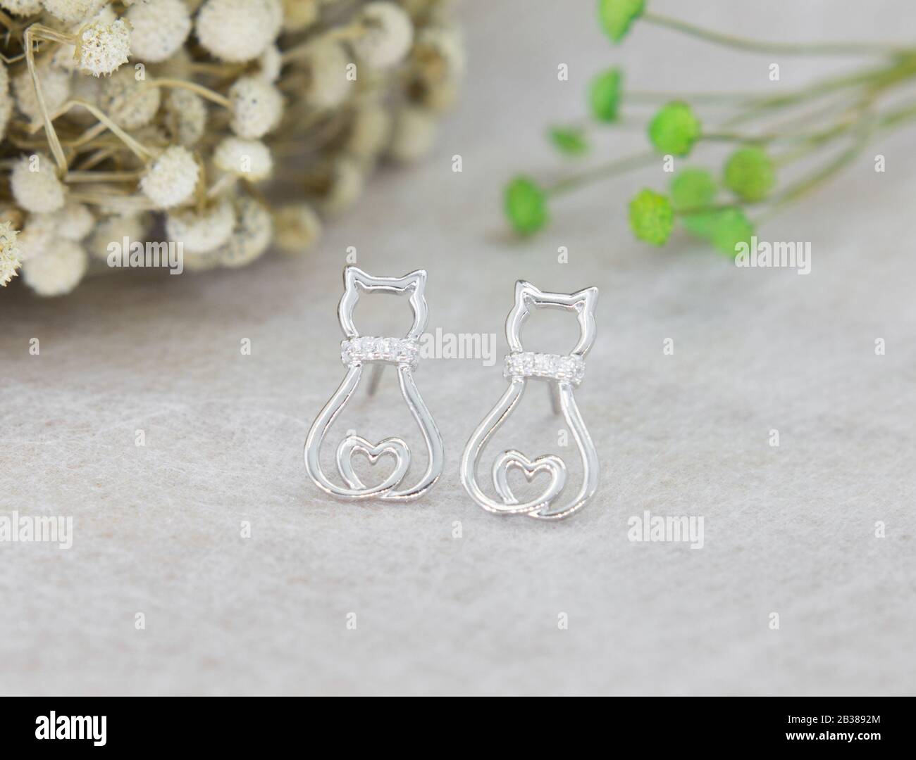 Une paire de superbes boucles d'oreilles en argent 925 en forme de chat décorées de diamant sur fond gris Banque D'Images