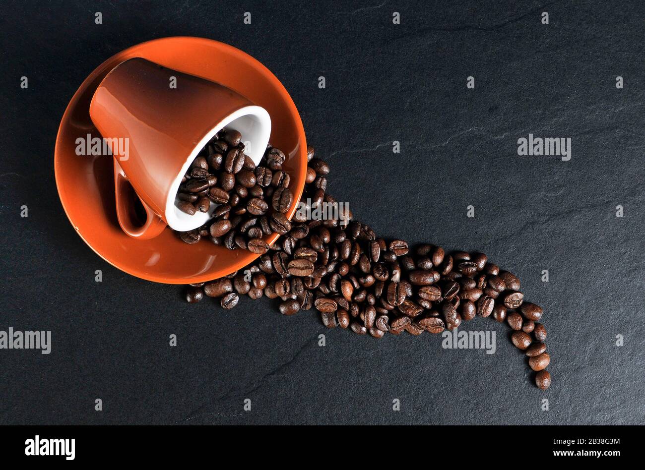 Grains de café débordant d'une tasse et d'une soucoupe Banque D'Images
