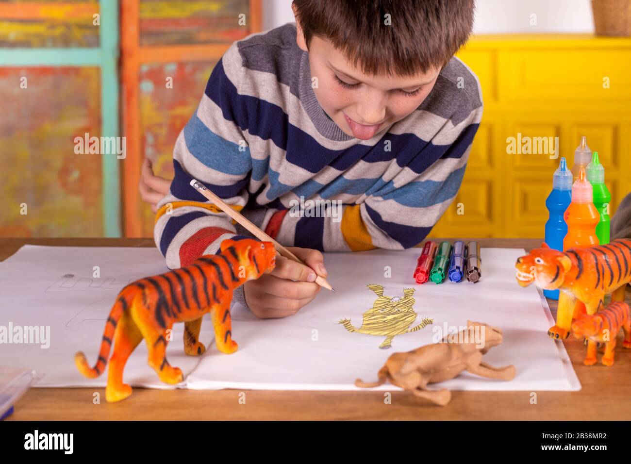 Garçon assis à une table dessinant un tigre. Banque D'Images