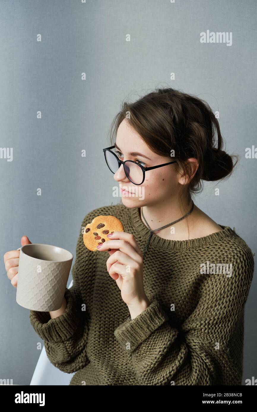 jeune fille à poil brun en verres boire du thé avec des gâteaux seuls Banque D'Images
