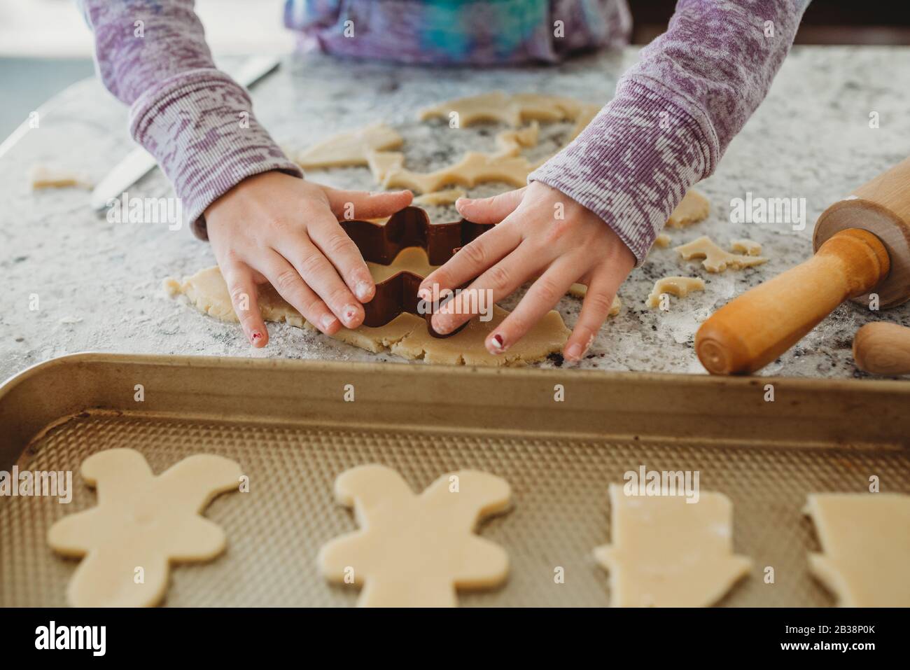 Les mains de jeunes filles utilisent un emporte-pièce sur la pâte à biscuits Banque D'Images