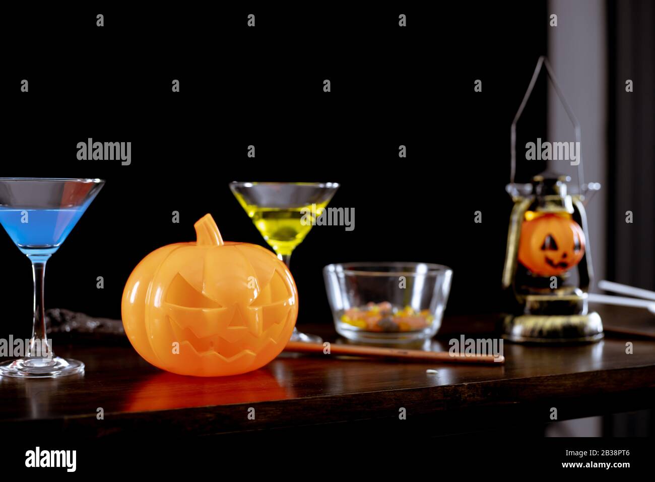Citrouilles fantômes, bonbons et boissons sur la table à la fête d'Halloween dans la nuit sur fond sombre. Banque D'Images