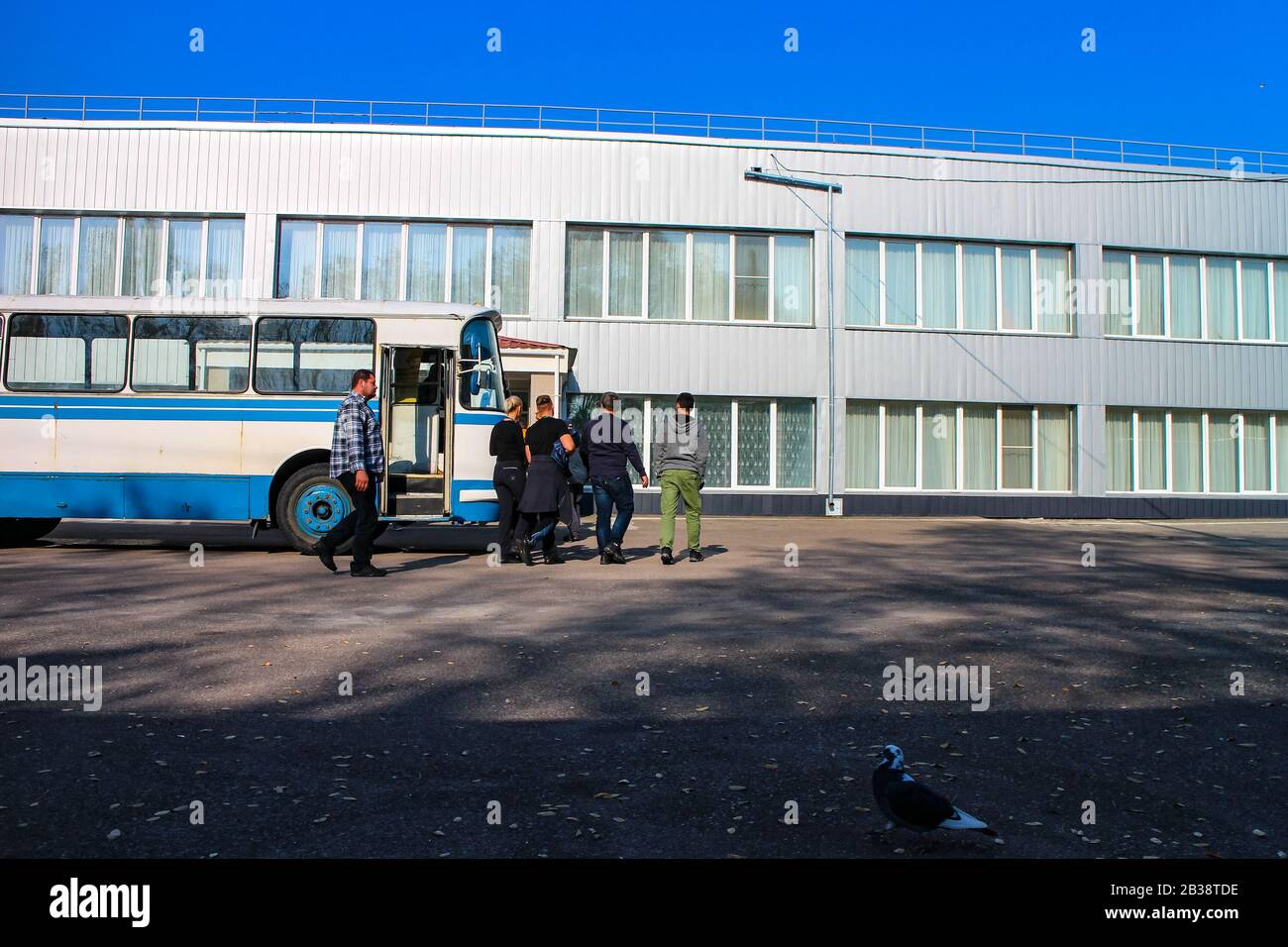 Un groupe touristique sombre quitte un bus à l'ancienne de l'ère soviétique pour entrer dans la cantine près du réacteur de Tchernobyl. Banque D'Images