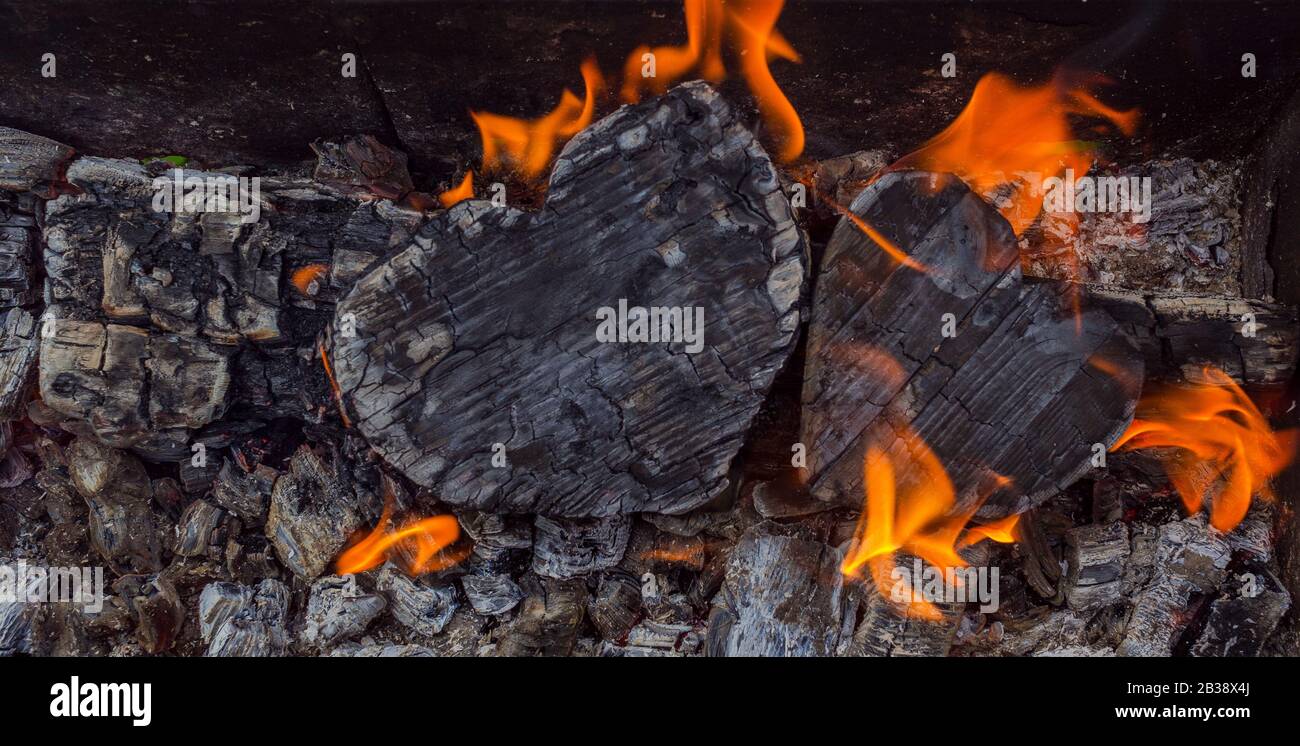 Charbons chauds et bois brûlants sous forme de coeur humain. Charbon de bois brillant et flamboyant, feu rouge vif et cendres. .gros plan, vue de dessus. Banque D'Images
