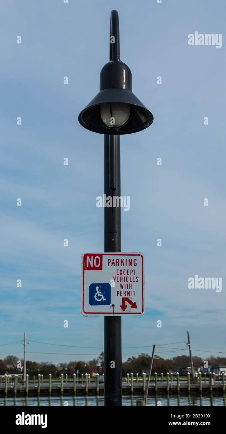 Un poteau de lampe à une marina locale a un panneau affiché qui lit, pas de parking sauf les véhicules avec permis, pour les plaisanciers handicapés à se garer. Banque D'Images