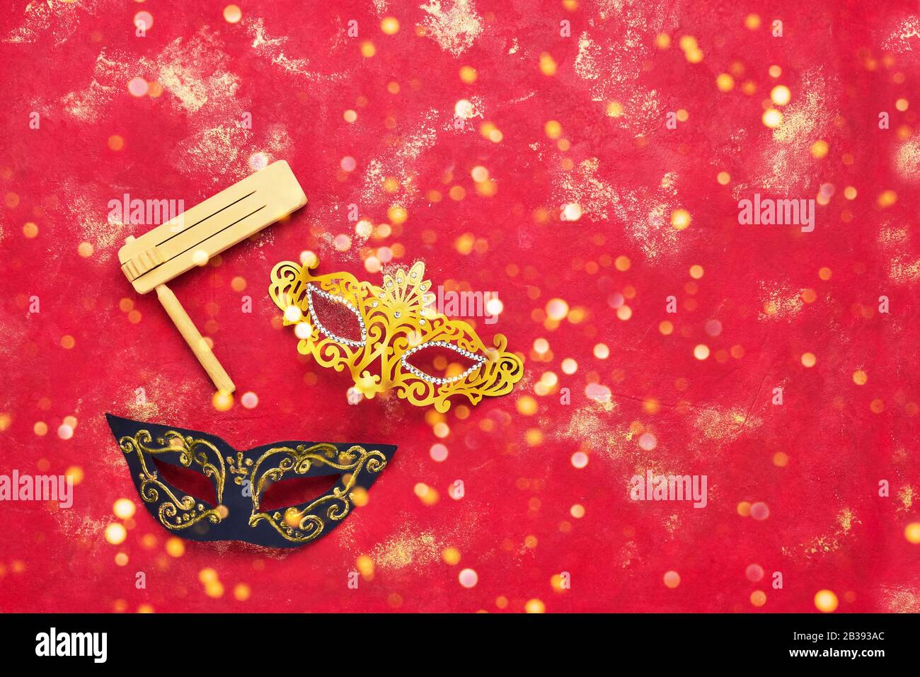 Masque de carnaval et grille en bois sur fond rouge vif. Plat du concept de célébration du Carnaval de Purim. Banque D'Images
